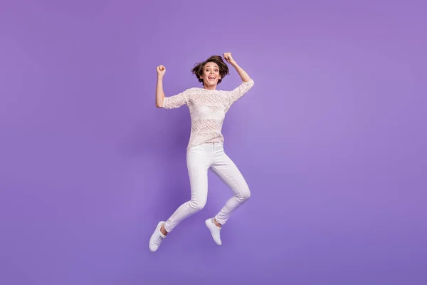 Foto de comprimento total de engraçado sorte jovem mulher usar camisa de malha saltando altos punhos em ascensão isolado cor violeta fundo — Fotografia de Stock