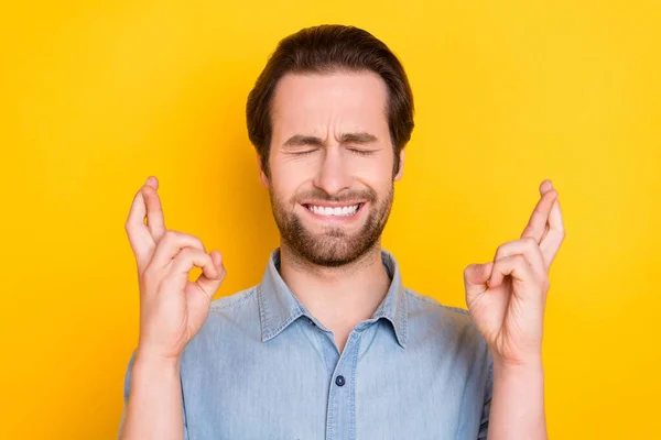 Фотопортрет молодого человека надежды на удачу со скрещенными пальцами изолирован на ярком желтом фоне — стоковое фото