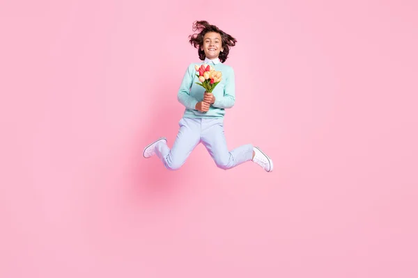 명랑 한 소년 점프 사진, 꽃 부케를 들고 핑크 색 배경 이 고립된 티셔츠를 입고 — 스톡 사진