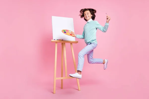 画家の少年ジャンプホールドパレットブラシを身に着けているターコイズシャツ孤立ピンク色の背景 — ストック写真