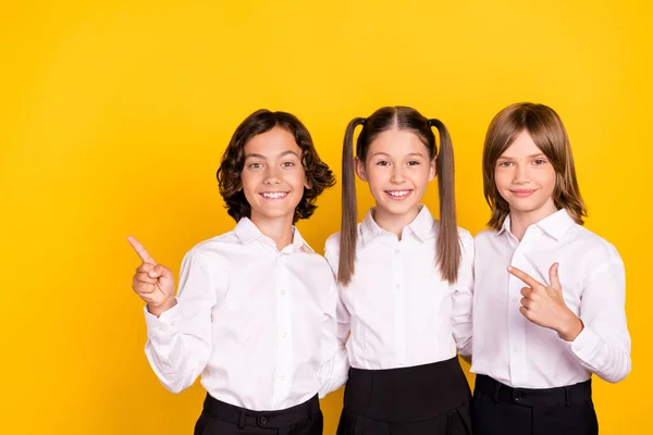 Fénykép három iskolás azt jelzi, ujj üres tér elősegíti értékesítés viselni fehér ing elszigetelt sárga színű háttér — Stock Fotó
