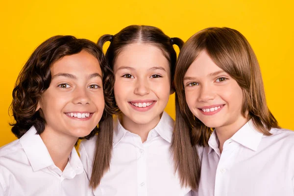 Foto de tres niños alegres mirar cámara brillante sonrisa blanca usar camisa blanca aislado color amarillo fondo —  Fotos de Stock