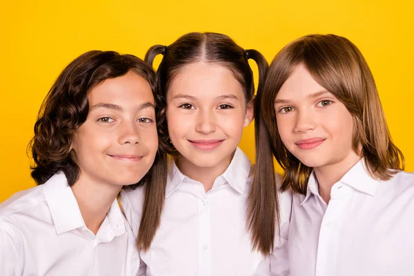 Photo of three cute peaceful kids lean together posing wear white shirt isolated yellow color background — Stock Photo, Image