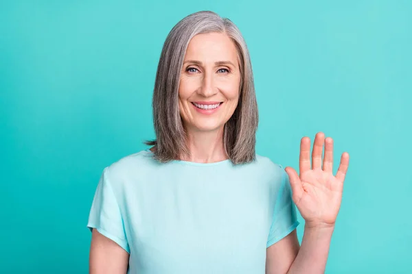 Портрет усміхненої веселої бабусі зрілої жінки показує руку привітання ізольовані на бірюзовому кольоровому фоні — стокове фото