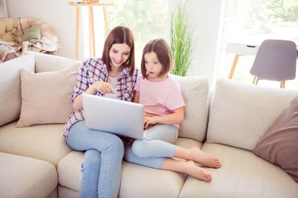 İki çekici kızın portresi divanda oturmuş dizüstü bilgisayar kullanarak evde video izlerken eğleniyorlar. — Stok fotoğraf