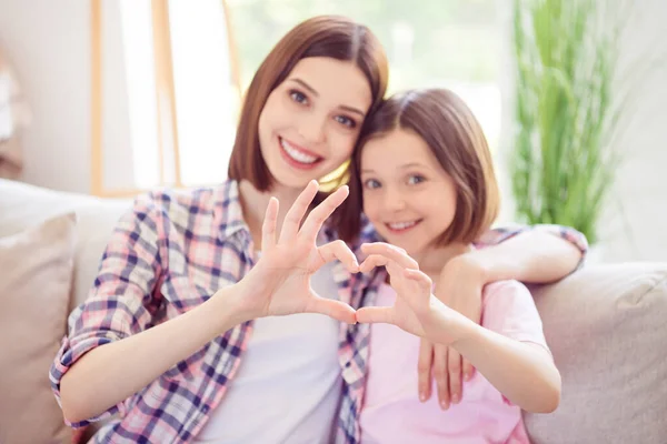 Foto av glada glada positiva systrar leende gör fingrarna hjärta form harmoni kärlek inomhus hus — Stockfoto