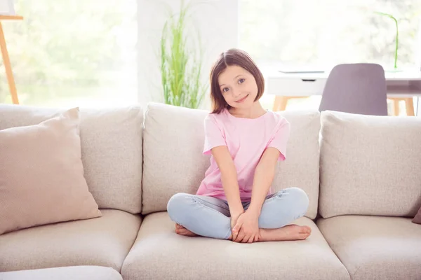 Portrét atraktivní veselý plachý roztomilý dívka tráví dovolenou sedí na divan odpočívá doma byt uvnitř — Stock fotografie