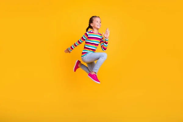 Profiel foto van dromerige sportieve actieve kleine meisje springen dragen gestreepte shirt jeans schoenen geïsoleerde gele kleur achtergrond — Stockfoto