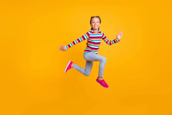 Foto de despreocupado corredor deportivo chica salto prisa rápido desgaste a rayas camisa jeans zapatos aislados de color amarillo fondo —  Fotos de Stock