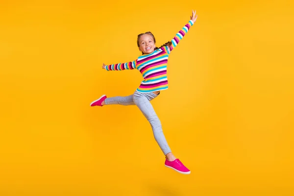 Foto von kleinen Mädchen springen machen modernen Tanz bewegen tragen gestreifte Hemd Jeans Turnschuhe isoliert gelbe Farbe Hintergrund — Stockfoto