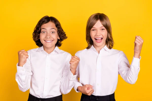 Foto von beeindruckt glücklichen Schulkindern Formalwear steigende Fäuste lächelnd isoliert gelbe Farbe Hintergrund — Stockfoto