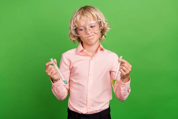 Foto de un joven infeliz dudoso niño pequeño cogido de la mano experimentos químicos aislados sobre fondo de color verde —  Fotos de Stock