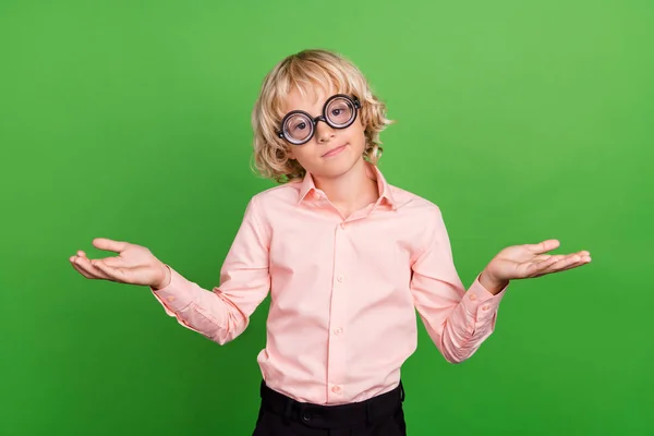 Photo of young puzzled by wear glasses shrug shoulders no idea isolated on shiny green color background — Stock Photo, Image