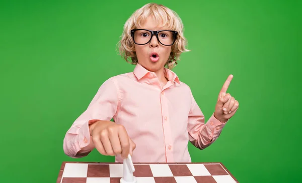 Foto de joven alegre niño positivo idea genio mover ajedrez de caballo aislado sobre fondo de color verde —  Fotos de Stock