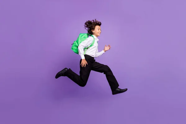 Foto de tamaño completo de la pequeña morena fresca niño correr desgaste bolso camisa pantalones zapatillas aisladas sobre fondo púrpura — Foto de Stock