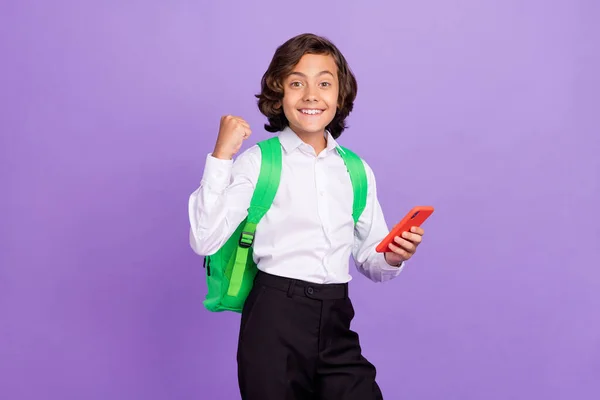 Fotografie Hurá malý brunet chlapec držet telefon nosit formalwear taška izolované na fialové barevné pozadí — Stock fotografie