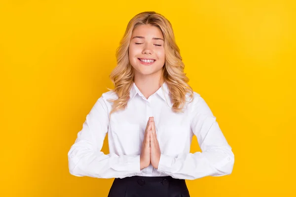 Foto de sonho inspirado estudante fechar os olhos segurar as mãos implorar desgaste camisa branca isolado cor amarela fundo — Fotografia de Stock