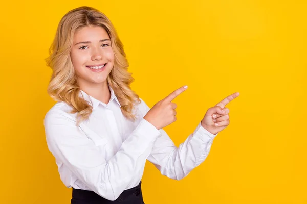 Foto di carino studentessa dito diretto che presenta spazio vuoto indossare camicia bianca isolato colore giallo sfondo — Foto Stock