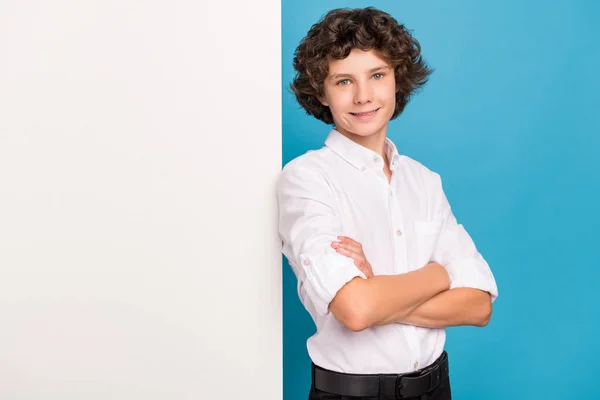 Foto van zoete zelfverzekerde schooljongen dragen witte shirt glimlachende armen gevouwen lege ruimte geïsoleerde blauwe kleur achtergrond — Stockfoto