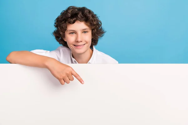 Foto von charmanten süßen Schuljungen tragen weißes Hemd lächelnd Zeigefinger Plakatwand leeren Raum isoliert blaue Farbe Hintergrund — Stockfoto