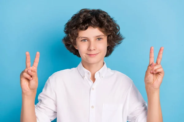 Foto van charmante mooie school jongen dragen witte shirt tonen v-tekens glimlachen geïsoleerde blauwe kleur achtergrond — Stockfoto