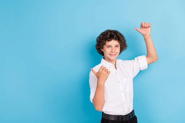 Foto van opgewonden mooie school jongen dragen witte shirt wijzen terug lege ruimte glimlachen geïsoleerde blauwe kleur achtergrond — Stockfoto