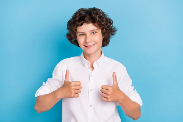 Foto van funky aantrekkelijke schooljongen dragen witte shirt glimlachen tonen duimen omhoog geïsoleerde blauwe kleur achtergrond — Stockfoto