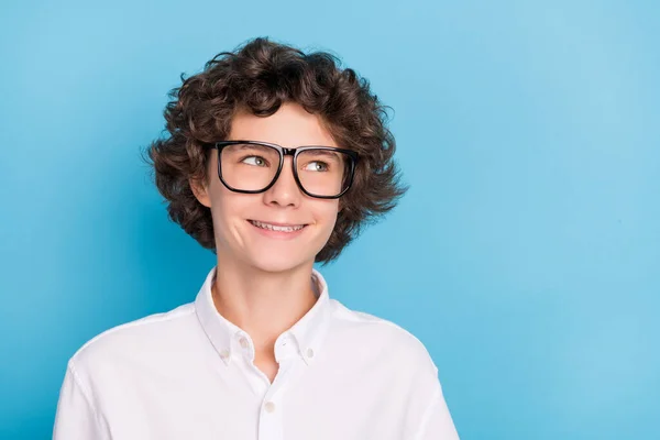 Foto do menino da escola sonhador amigável usar óculos de camisa branca olhando espaço vazio sorrindo isolado fundo de cor azul — Fotografia de Stock