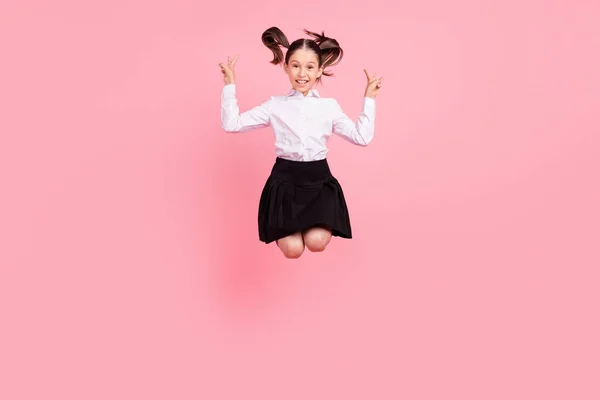 Foto de longitud completa de la pequeña niña positiva feliz salto hasta mostrar v-signo fresco aislado en el fondo de color rosa pastel —  Fotos de Stock