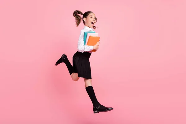 Full body photo of cheerful happy small brunette girl jump look empty space crazy copybook isolated on pink color background — Stock Photo, Image