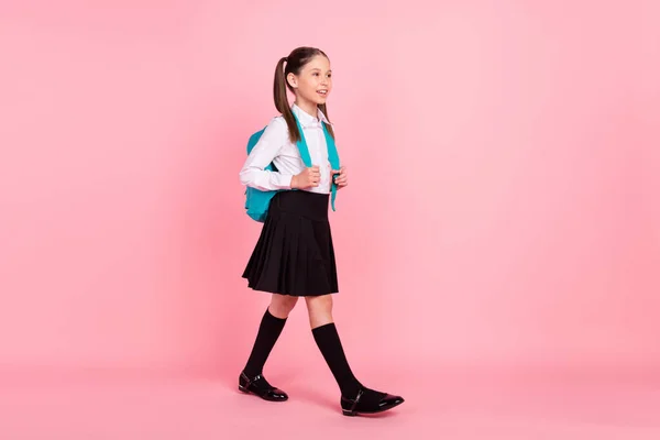 Full body photo of young small happy girl look walk empty space school wear bag isolated on pink color background — Stock Photo, Image