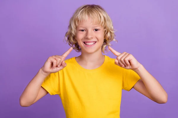 Photo de garçon positif indiquer doigt dent sain sourire porter jaune t-shirt isolé couleur pourpre fond — Photo