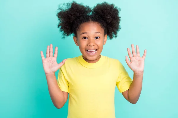 Фото смешной брюнетки маленькая девочка руки вверх носить желтую футболку изолированы на бирюзовом фоне — стоковое фото