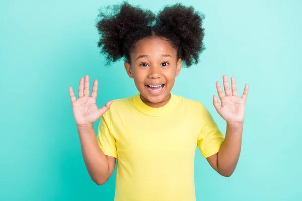 写真の面白いブルネットの女の子の手をアップ着用黄色tシャツ絶縁上のティール色の背景 — ストック写真