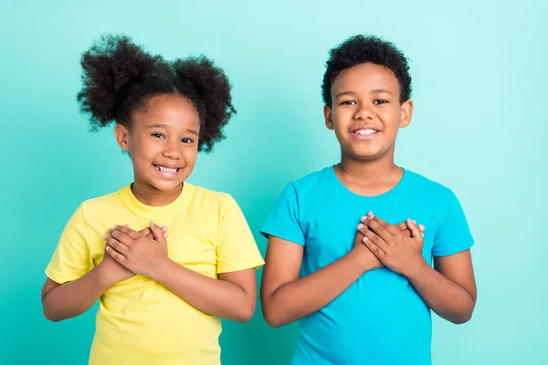 Portrait of affectionate cheerful friends friendship touching heart dedication isolated over bright teal turquoise color background