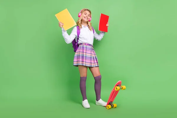 Vista completa del tamaño del cuerpo de la chica bastante alegre escuchando patín de montar pop estudiar aislado sobre fondo de color verde — Foto de Stock