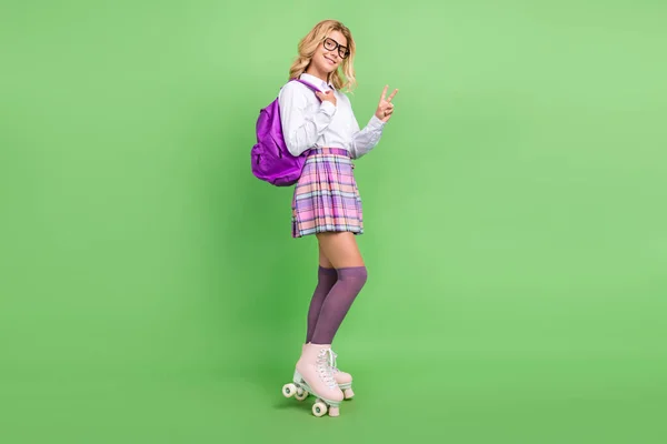 Повний розмір тіла приваблива весела дівчина катається на ковзанах, що показують v-знак ізольовано на фоні зеленого кольору — стокове фото