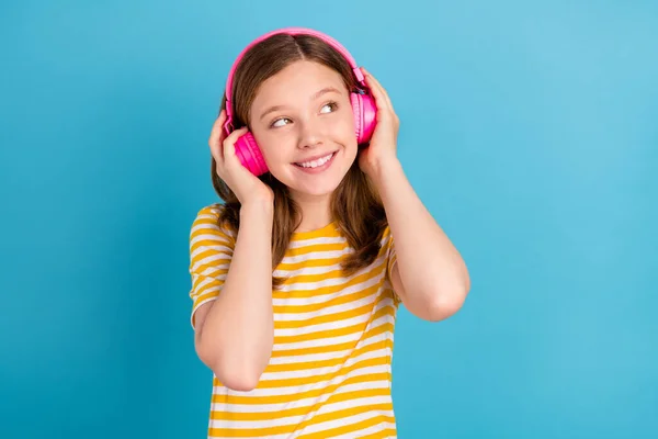 Porträt von entzückenden niedlichen Schulkind Touch-Kopfhörer sehen leeren Raum isoliert auf blauem Hintergrund — Stockfoto