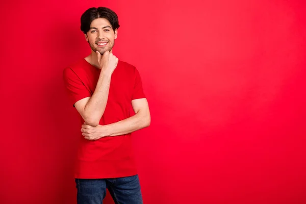 Foto de alegre chico inteligente mano barbilla look cámara sonrisa blanca usar camiseta roja aislado color rojo fondo — Foto de Stock
