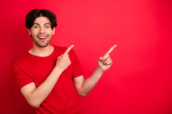 Foto van opgewonden gekke man geven vinger lege ruimte bevorderen verkoop dragen rood t-shirt geïsoleerde rode kleur achtergrond — Stockfoto