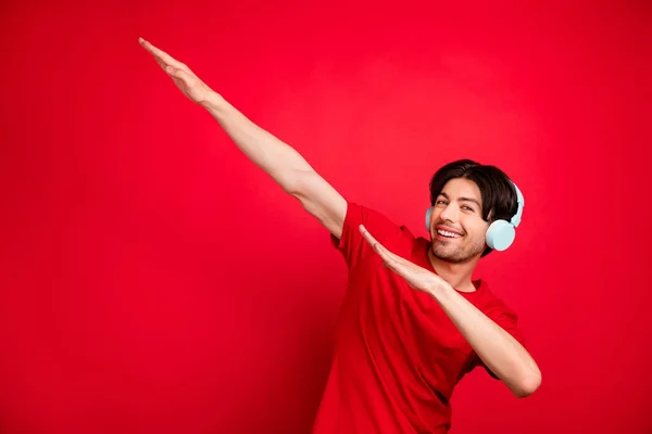 Foto van de jongeman blij positieve glimlach luisteren muziek koptelefoon dansen dab hip-hop geïsoleerd over rode kleur achtergrond — Stockfoto