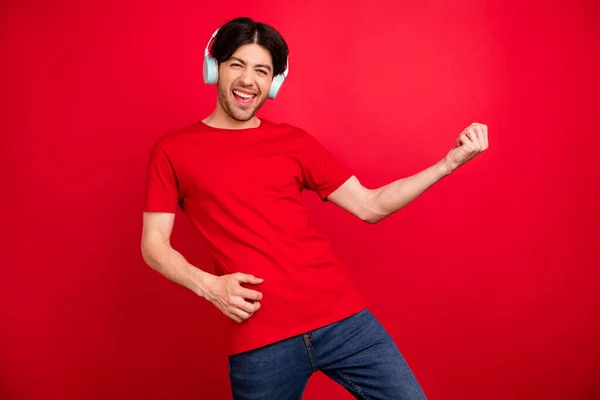 Foto de joven feliz sonrisa positiva jugar guitarra música amante auriculares aislados sobre fondo de color rojo — Foto de Stock