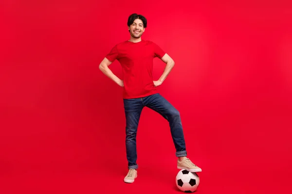 Pełna długość zdjęcie młodego człowieka szczęśliwy pozytywny uśmiech grać w piłkę nożną gra sportowa izolowane na czerwonym tle koloru — Zdjęcie stockowe