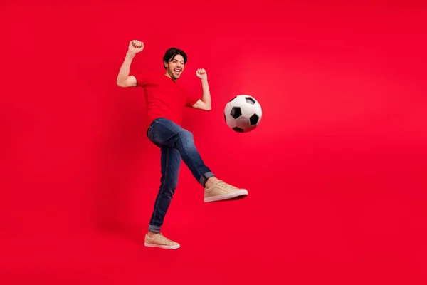 축구 선수의 다리 뒷발 가죽 공을 차는 사진붉은 티셔츠 청바지를 입고 있다. — 스톡 사진