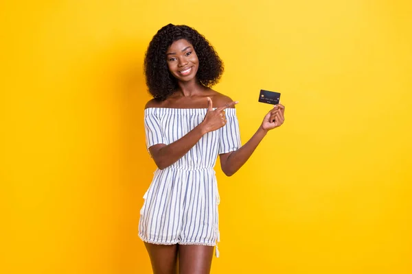 Retrato de bela menina alegre na moda segurando na mão demonstrando cartão bancário isolado sobre fundo de cor amarelo brilhante — Fotografia de Stock