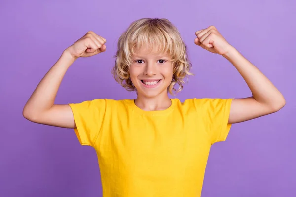 강력 한 아이가 손을 드는 사진은 이두근 이 노란 티셔츠외진 보라색 배경을 착용하는 것을 보여준다 — 스톡 사진