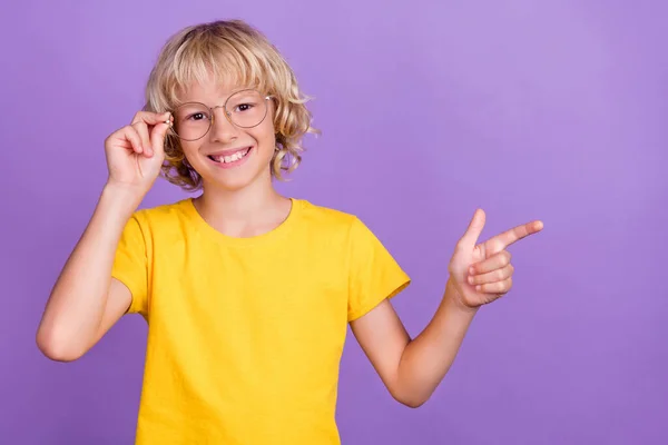 Foto de colegial dulce divertido desgaste amarillo camiseta brazo gafas sonriendo dedo dedo vacío espacio aislado color violeta fondo —  Fotos de Stock