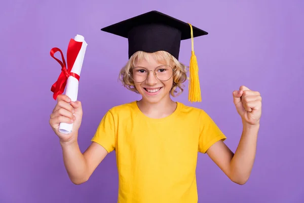 Φωτογραφία από έξυπνο τυχερό αγόρι σχολείο φορούν κίτρινα γυαλιά t-shirt αποφοιτώντας δευτεροβάθμιο επίπεδο αυξάνεται γροθιά χαμογελώντας απομονωμένο πορφυρό φόντο χρώμα — Φωτογραφία Αρχείου