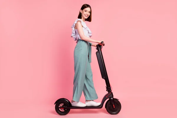 Perfil de cuerpo completo lado de la foto de la joven feliz sonrisa positiva viaje bicicleta eléctrica aislada sobre fondo de color rosa —  Fotos de Stock