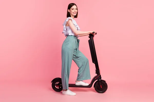 Foto lateral de perfil de longitud completa de niña feliz sonrisa positiva fin de semana paseo eco scooter aislado sobre fondo de color rosa —  Fotos de Stock